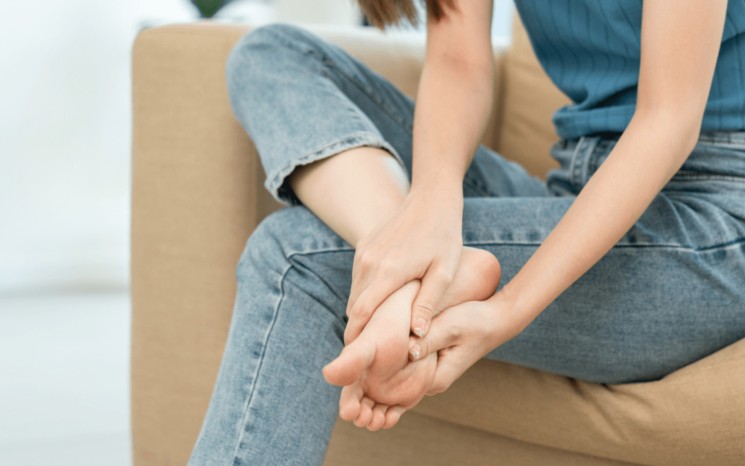 Woman in blue t-shirt and jeans holding foot